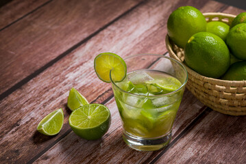Glass of caipirinha with lemon on an aged wooden table. Typical Brazilian drink made with cachaca, lemon, ice and sugar.