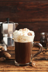 Coffee drink with nutmegs and whipped cream on wooden table