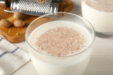 Milk with nutmeg powder on white table, closeup