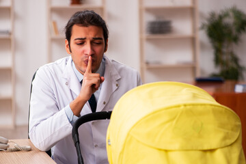Young male doctor looking after new born in the clinic