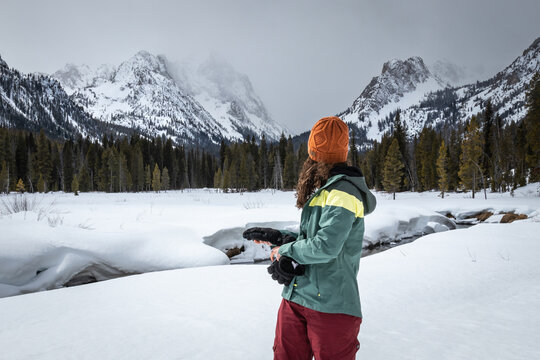 Woman looks over her shoulder to the grand landscape of the sawtooth mountains
