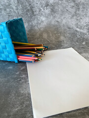 White sheets and a set of colored pencils in a holder to draw