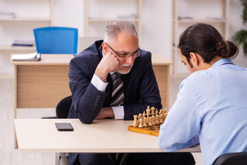 Two businessmen playing chess in the office