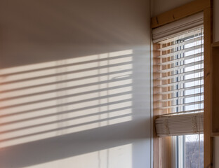 Ombre de stores sur un mur à côté d'une fenêtre lumière du soleil