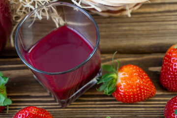 Strawberry in basket and on table on wooden background, strawberry juice in jug