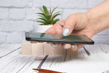 Women holding a phone in their hand, sending a message or looking at market quotes, business concept
