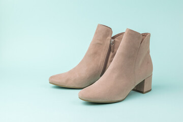 Fashionable women's suede ankle boots on a light turquoise background.