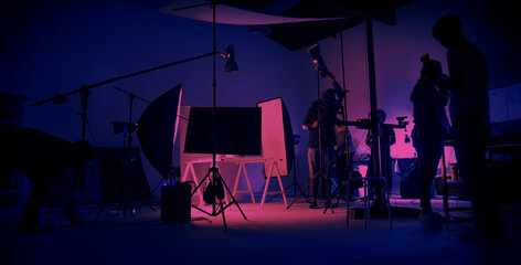 Neon Blue pink color shooting. behind the scene of video production set up in the big studio. Crew team working and camera equipment in silhouette. Movie production industry. Lighting set up. - obrazy, fototapety, plakaty