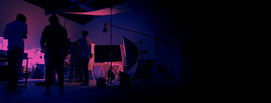 Neon Blue pink color shooting. behind the scene of video production set up in the big studio. Crew team working and camera equipment in silhouette. Movie production industry. Lighting set up.