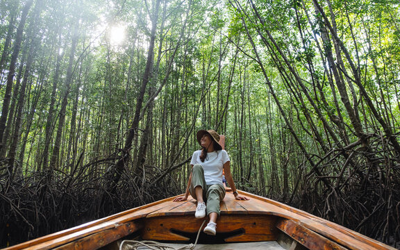 Portrait image of a beautiful young asian woman sitting on a long tail boat while traveling the mangrove forest