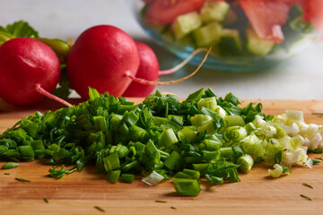 chopped radishes and green onions on a cutting board