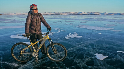 Fototapeta na wymiar Man is riding bicycle on the ice. Ice of frozen Lake Baikal. Rid