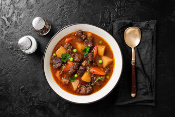 Irish stew made with beef, potatoes, carrots and herbs. Traditional St patrick's day dish. Black background, top view.