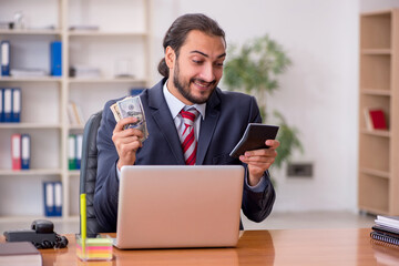 Young male bookkeeper holding banknotes and calculator