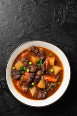 Irish stew made with beef, potatoes, carrots and herbs. Traditional St patrick's day dish. Black background, top view.
