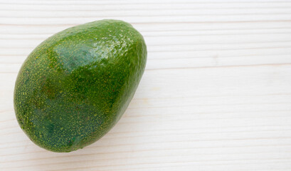 A ripe avocado sits on a light-colored chopping board