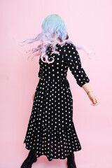 Young woman in a blue colorful wig and polka dot dress shaking her head