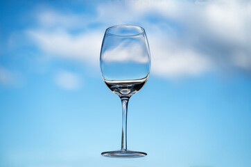 Floating empty wine glass in front of a blue sky