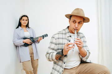 Thoughful man and woman playing thier instruments inside a room.