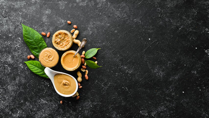 Fototapeta na wymiar Peanut butter and nuts on a black stone background. Healthy food. Top view.
