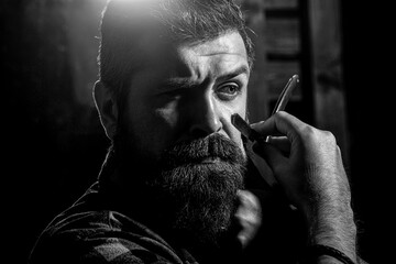 Vintage straight razor. Mens haircut. Man in barbershop. Handsome bearded hairdresser is holding a straight razor while barbershop. Black and white