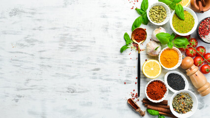 Set of Indian spices, basil and herbs on a white wooden background. Top view. Free space for text.