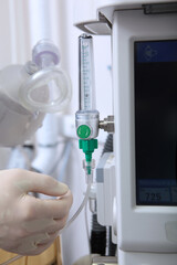 The anesthesiologist turns on the machine for artificial ventilation of the lungs. Surgery under anesthesia.Oxygen level sensor. Saving lives. Concept of healthcare.Vertical photo.