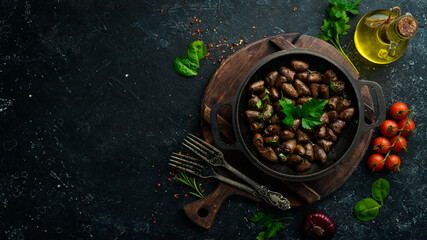 Fried chicken hearts with parsley and spices in a metal pan. Top view. Free space for text.