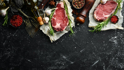 Two raw beef steak ribeye on a stone table. Top view. Free space for your text.