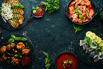 Set meal of meat, seafood and vegetables on the black stone table. Top view. Free space for your text.