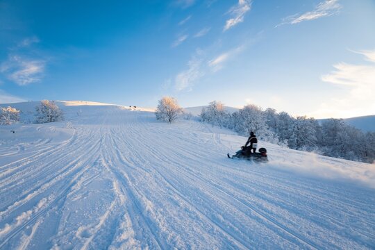 Vacationers cheerful at the ski resort tourists in the mountain Carpathian valley ride fast snowboards and skis