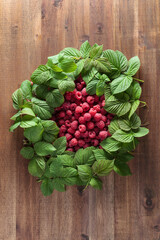 Ripe raspberries with leaves on an old wooden table.