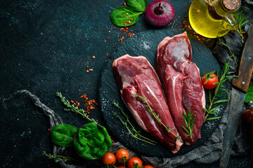 Raw fresh duck fillet with rosemary and spices. On a black background. Top view.