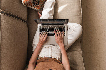 Young woman workin on laptop computer lying on the couch. Work at home at quarantine, freelancer...