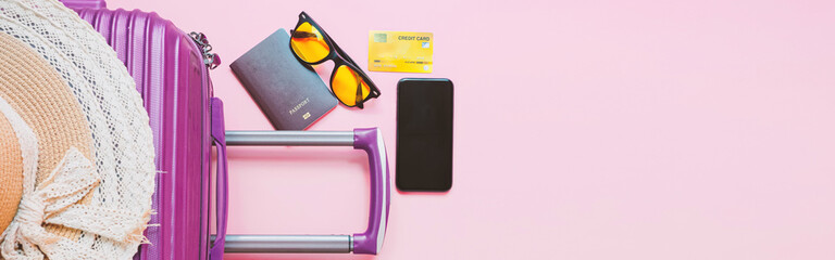 summer travel concept from credit card and suitcase with summer collection on pink background. web banner size.
