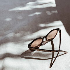 Female sunglasses on white background with blurred sunlight shadows. Minimal aesthetic fashion...