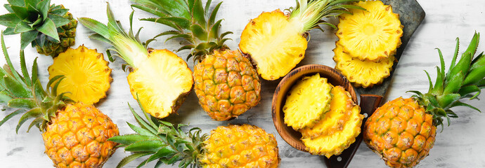 Pineapple collection. Whole and sliced pineapple, on a white wooden background. Top view. Free space for text. - obrazy, fototapety, plakaty