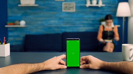Point of view freelencer man in office studio holding mock up green screen chroma key phone. Caucasina female browsing on internet using isolated device for social media connection