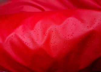 Large drops of water on a red textile with a waterproof effect. Water-repellent impregnation....