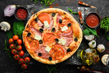 Traditional pizza with bacon, tomatoes and cheese. On a black stone background. Free space for text.