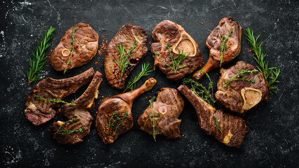 Set of juicy grilled steaks and meat. Top view. Flat lay top view on black stone cutting table.