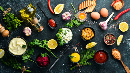 Set of sauces and spices on stone background. Sauces: mayonnaise, ketchup, tartare, barbecue and...