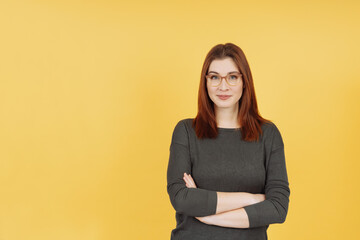 Confident pert young woman wearing glasses standing with folded arms