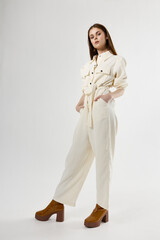 Woman in white jumpsuit with hands in pockets bottom view in full growth