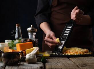 Fototapeta na wymiar the chef prepares by rubbing cheese for pasta. Different types of cheese. The concept of cooking dishes with cheese. Cooking and restaurant business, menu