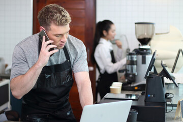 Portrait of a handsome barista in apron at the bar of the modern cafe cheerful men baristas wearing aprons working at the counter in cafe indoors, talking , owned business , new life