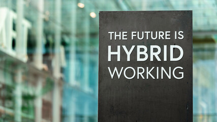 The Future of Work is Hybrid sign in front of a modern office building