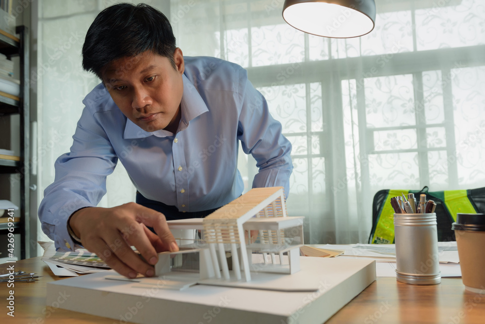 Poster architect-designer working with model of modern box house while thinking about concept of building a