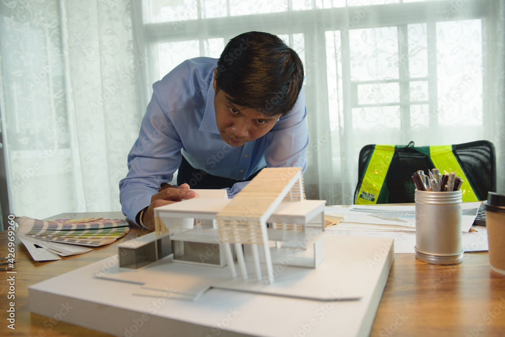 Poster architect-designer working with model of modern box house while thinking about concept of building a