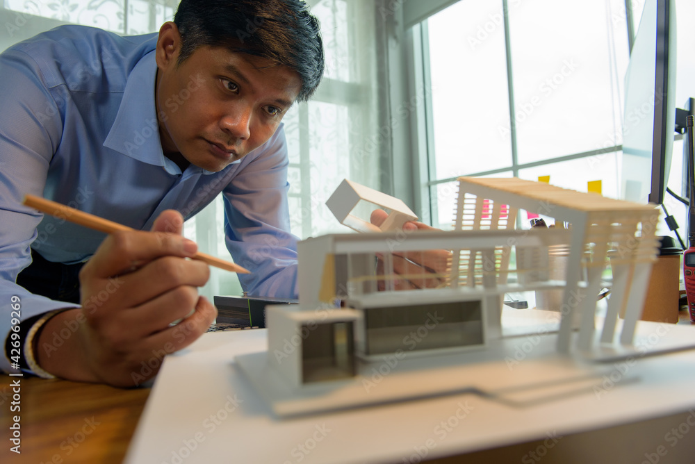 Poster architect-designer working with model of modern box house while thinking about concept of building a